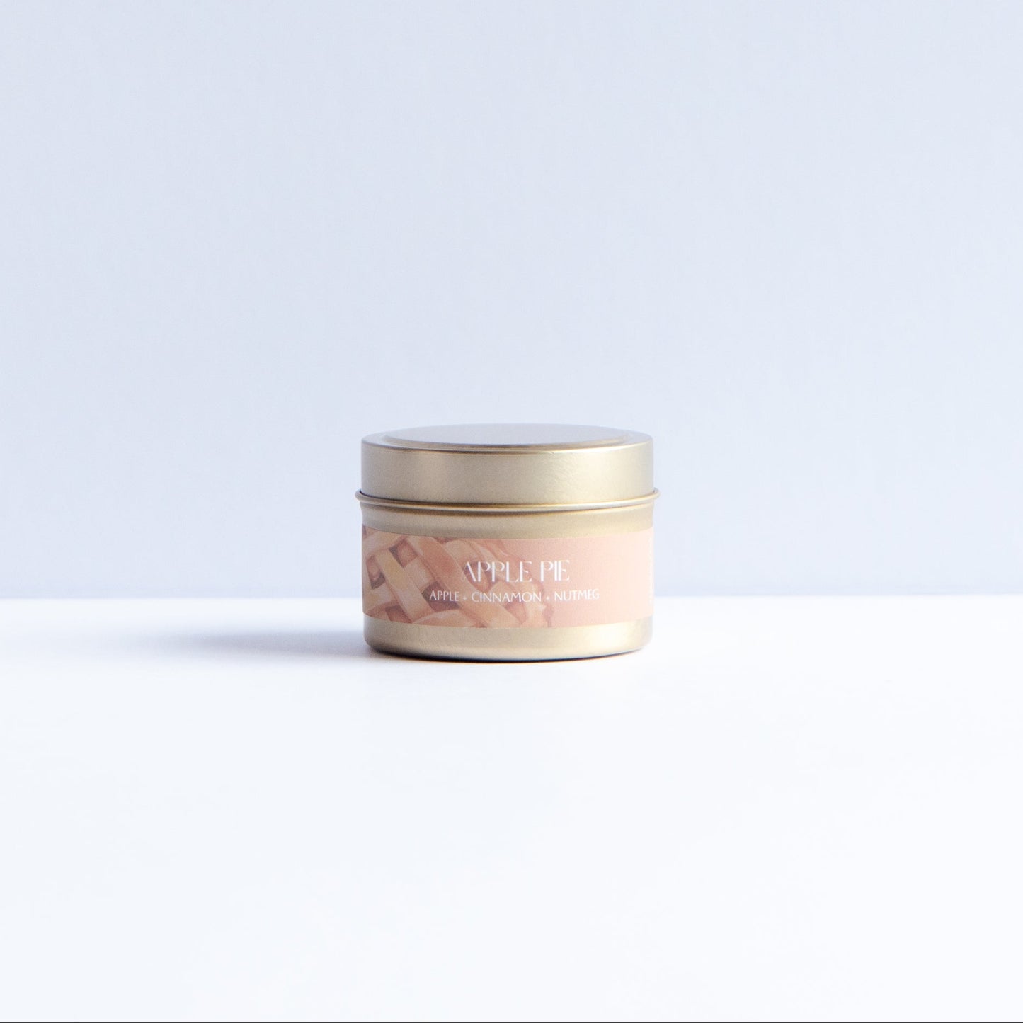 A small round cosmetic jar with a gold lid and a light peach label reading 'LUXE' and 'Rose', placed on a white surface against a pale blue-gray background.