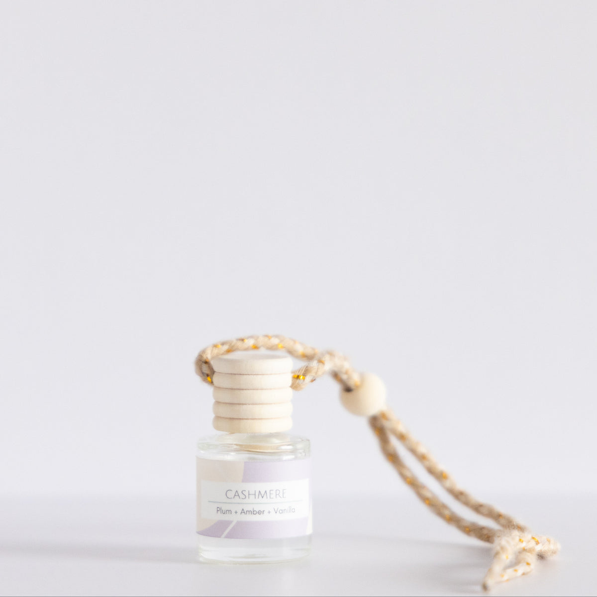 Small glass bottle with a gold cap and string on a light gray background