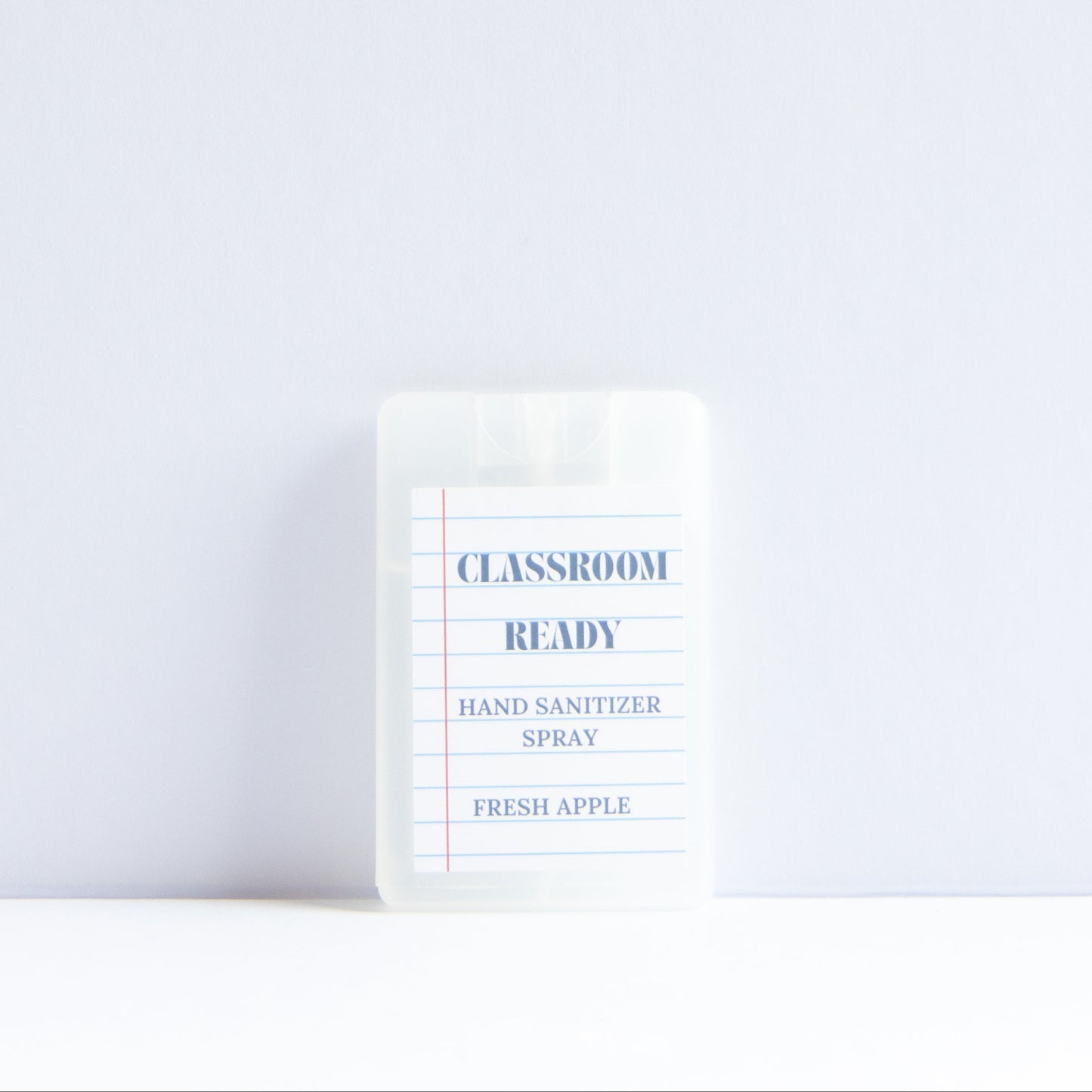 A small clear plastic bottle of Classroom Ready Hand Sanitizer Spray in Fresh Apple scent, standing upright on a white surface against a light gray background.