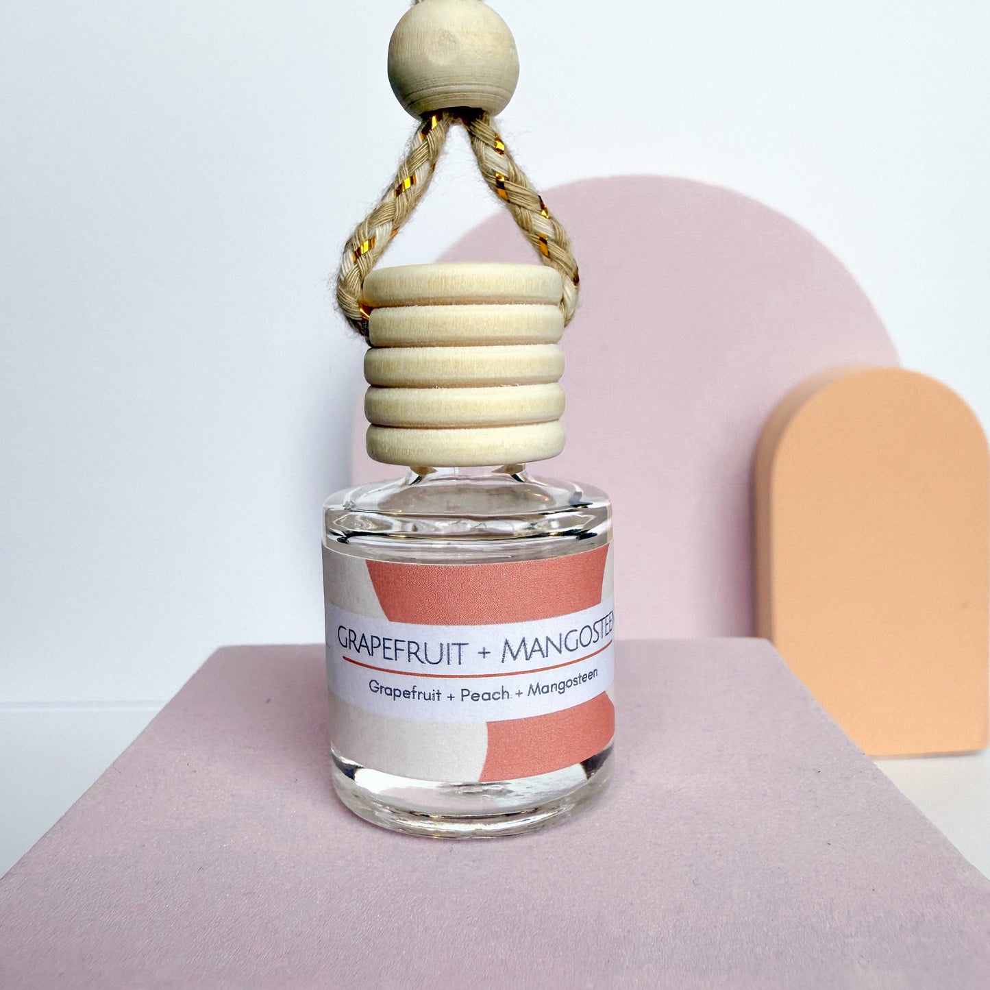 Glass diffuser bottle with wooden top on a pink surface