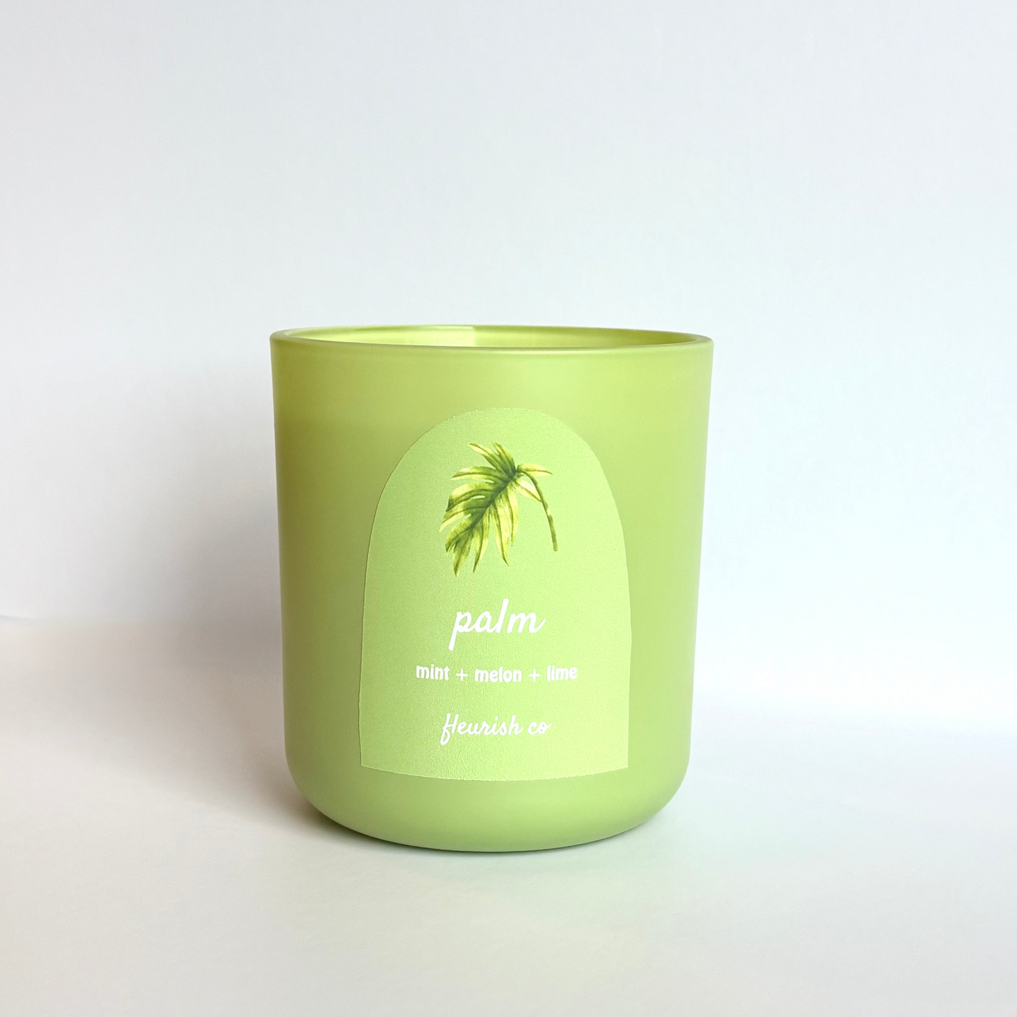 Green candle with a palm leaf design on a white background