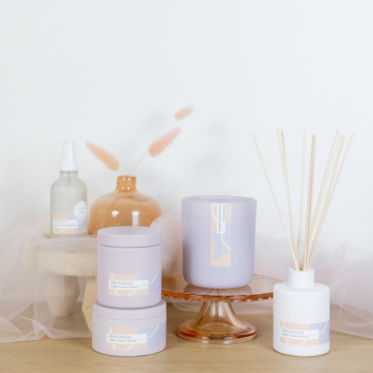 Decorative items including candles and diffusers on a wooden surface with a white background