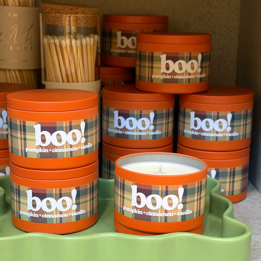 Stacks of 'boo!' themed candles on a green tray with plaid labels.
