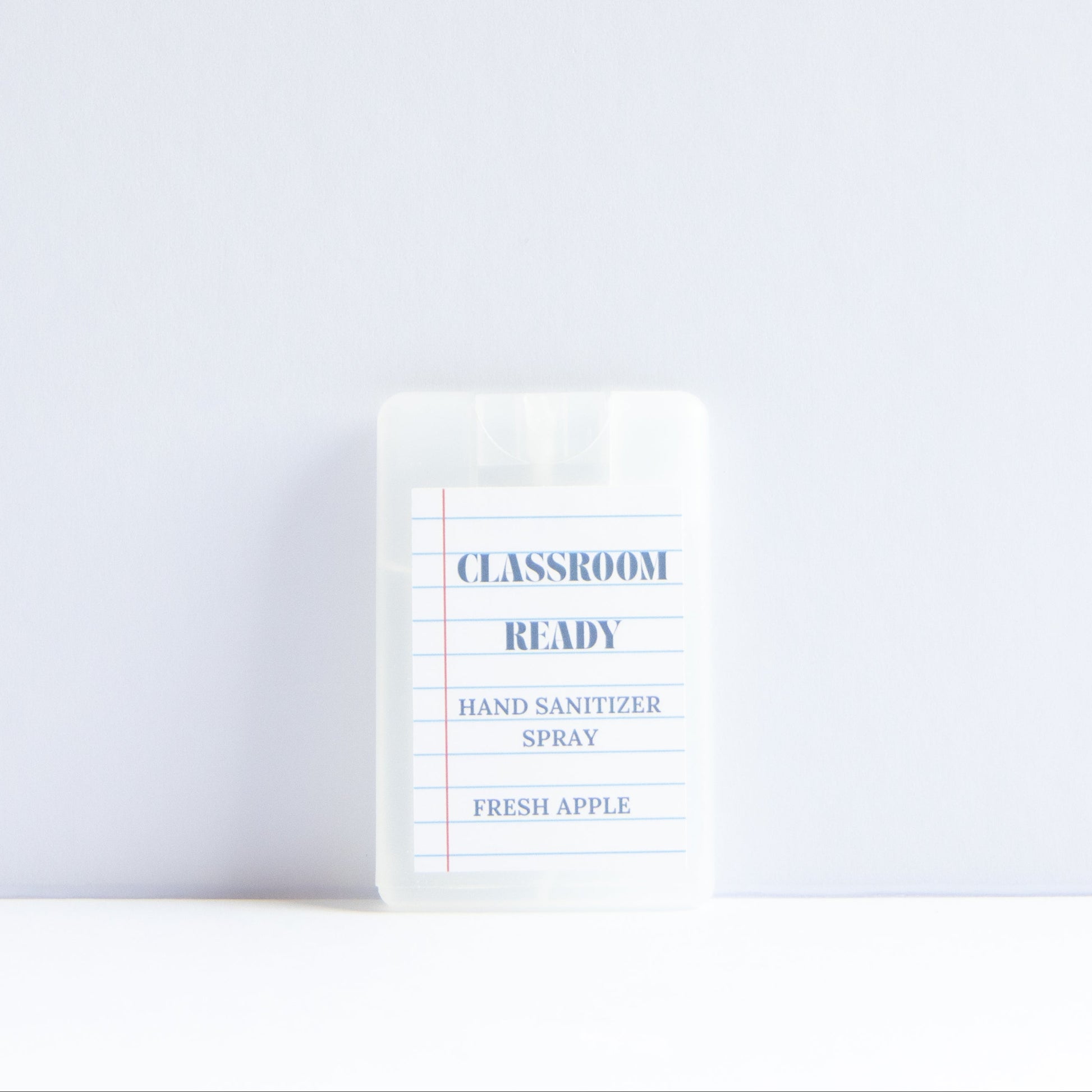 A small clear plastic bottle of Classroom Ready Hand Sanitizer Spray in Fresh Apple scent, standing upright on a white surface against a light gray background.