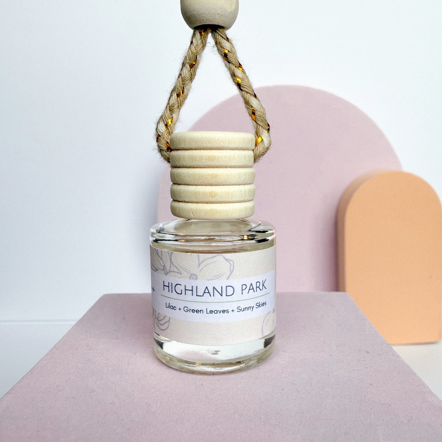 Glass bottle with wooden top labeled 'Highland Park' on a pink surface with a white background