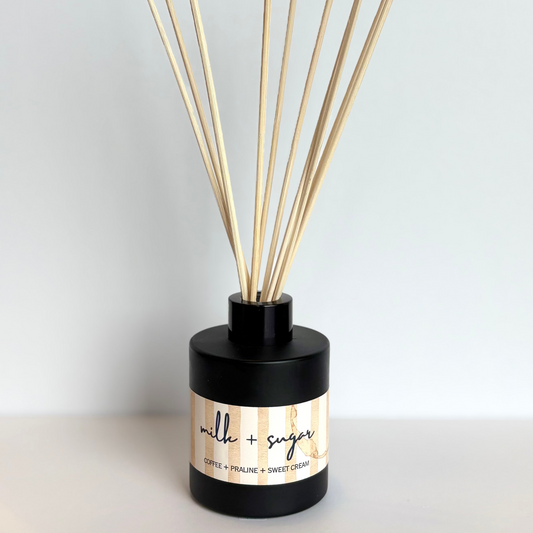 Diffuser with wooden sticks labeled 'milk + sugar' on a light background