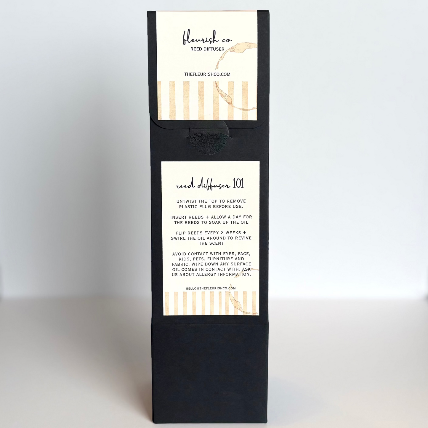 Black gift box with white labels on a white surface