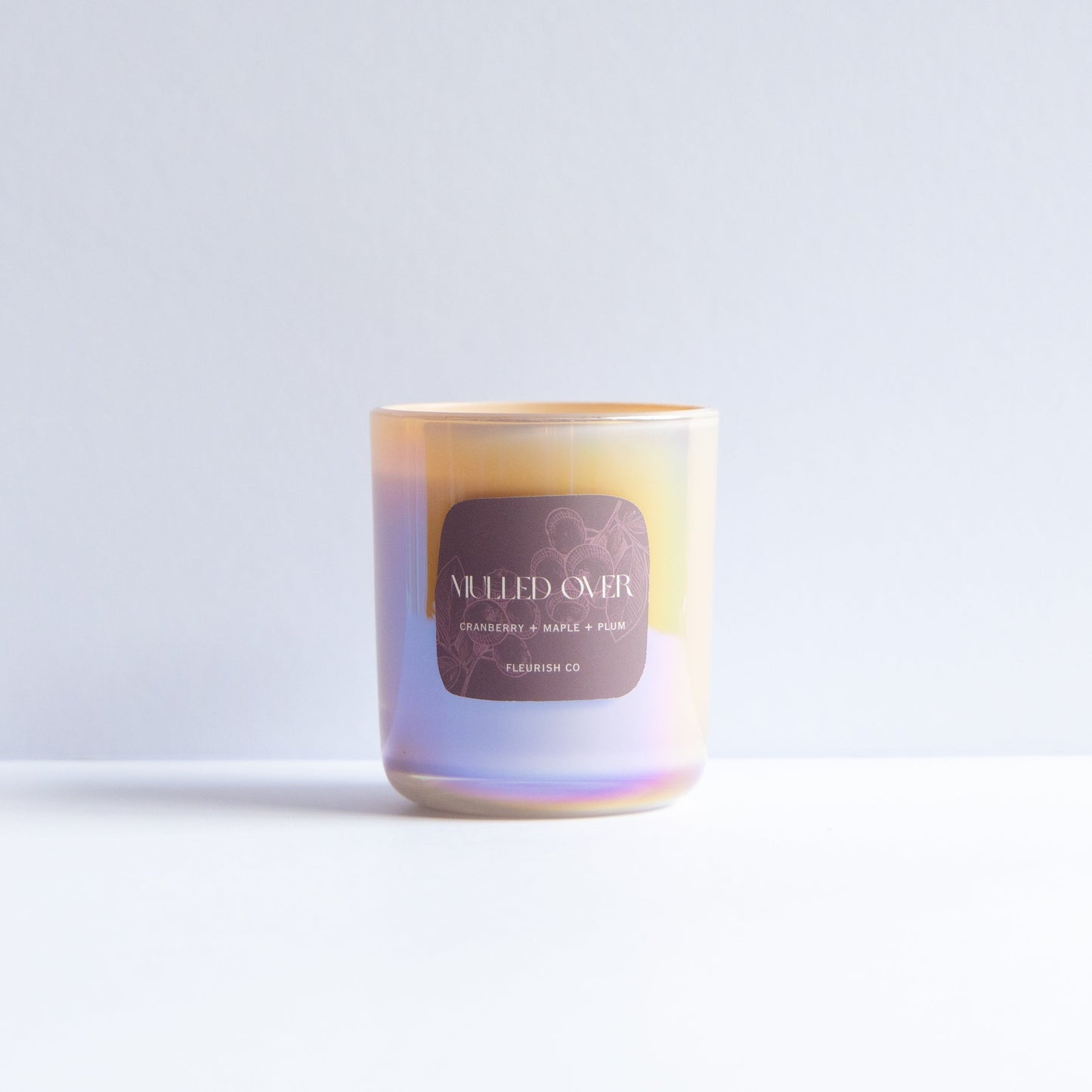 A single iridescent glass candle jar with a gold-toned rim and a dark brown label reading 'MELTED OIL' and 'SANDWICH 03', photographed on a clean white surface against a pale gray background.