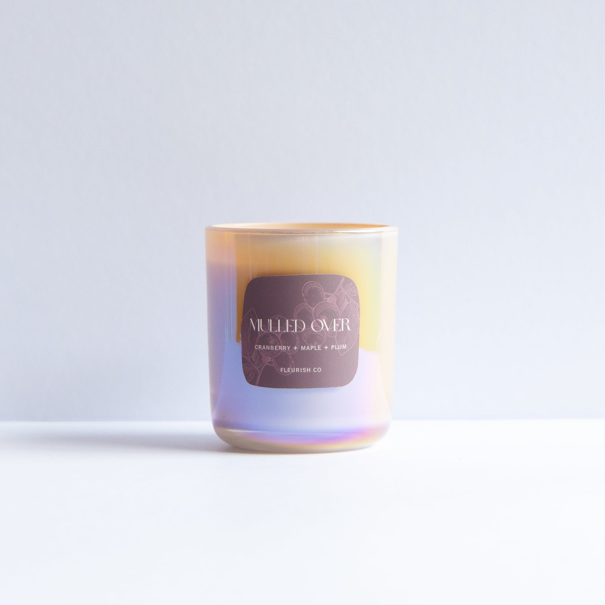 A single iridescent glass candle jar with a gold-toned rim and a dark brown label reading 'MELTED OIL' and 'SANDWICH 03', photographed on a clean white surface against a pale gray background.