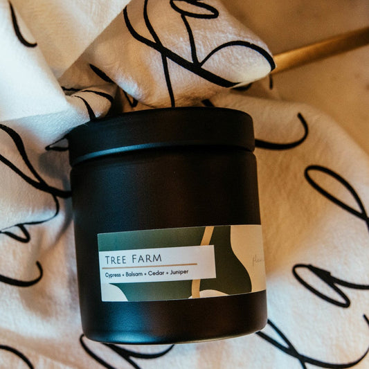 Black candle with a label on a decorative cloth with cursive text