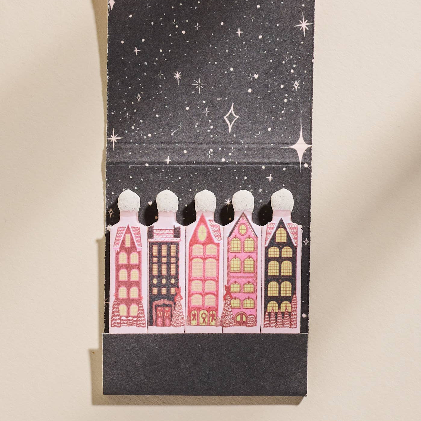 Matchbook with illustrated houses and starry night design on a beige background